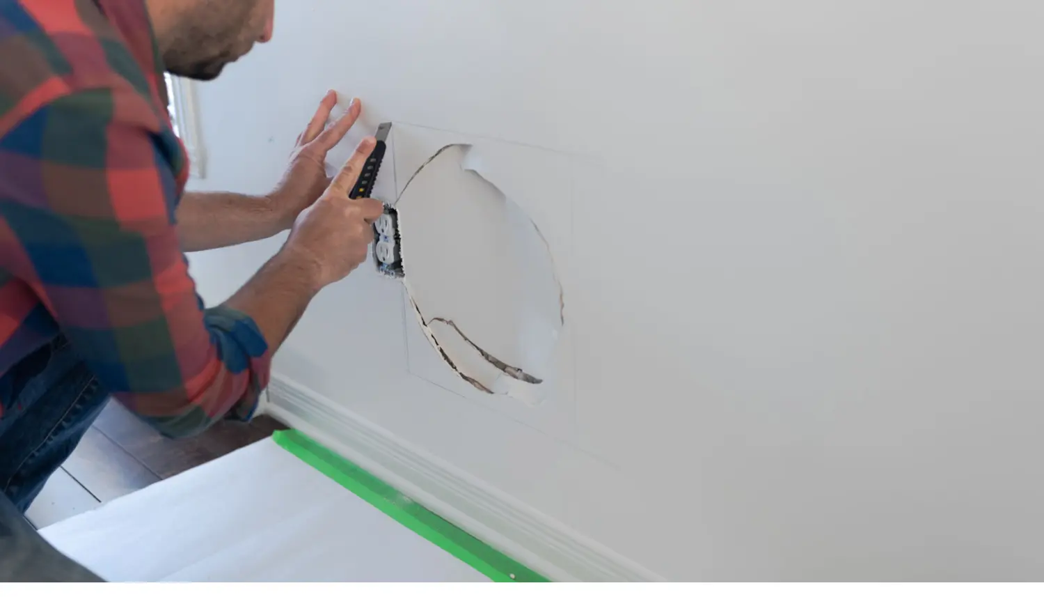 Expert Savannah drywall repair technician patching a damaged wall with a utility knife.